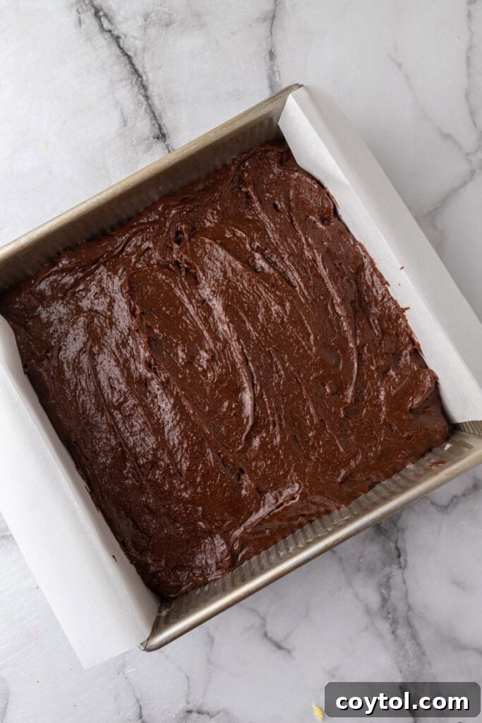 Brownie batter poured into a parchment-lined baking pan
