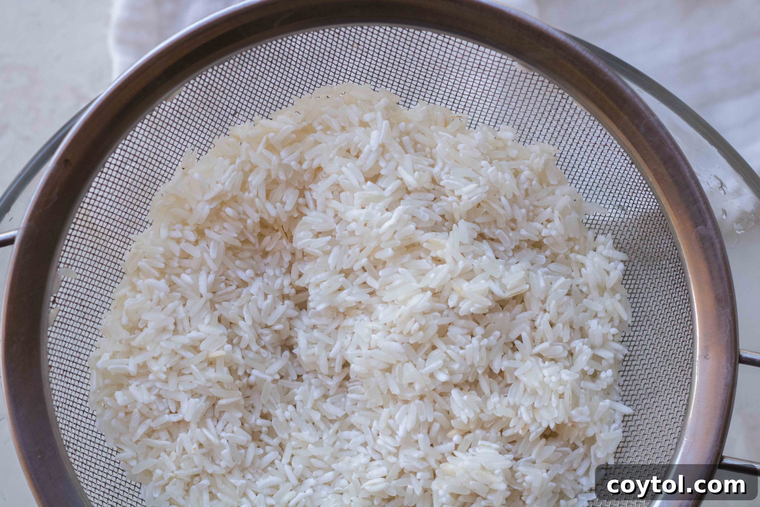 Cooked white rice being fluffed with a fork in a pot