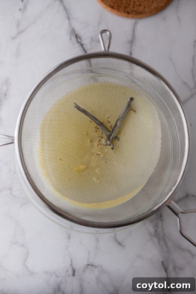 Velvet Vanilla Custard Ice Cream Made Simple 12 vanilla bean pod being removed from the strained custard