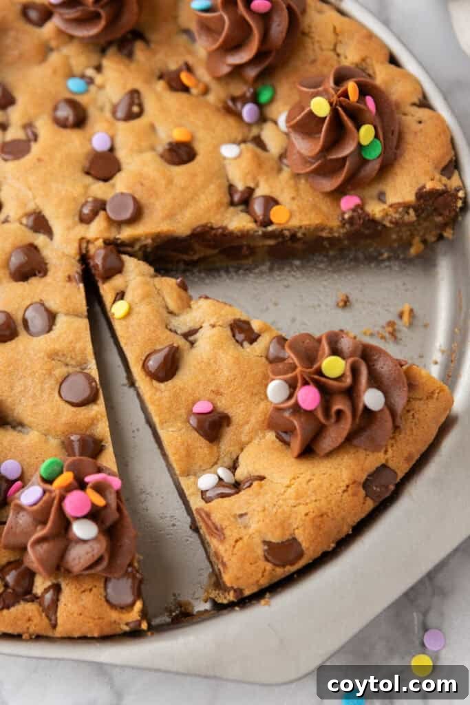 The Ultimate Homemade Chocolate Chip Cookie Cake 4 An overhead view of the finished chocolate chip cookie cake, frosted and decorated, sliced on a wire rack.