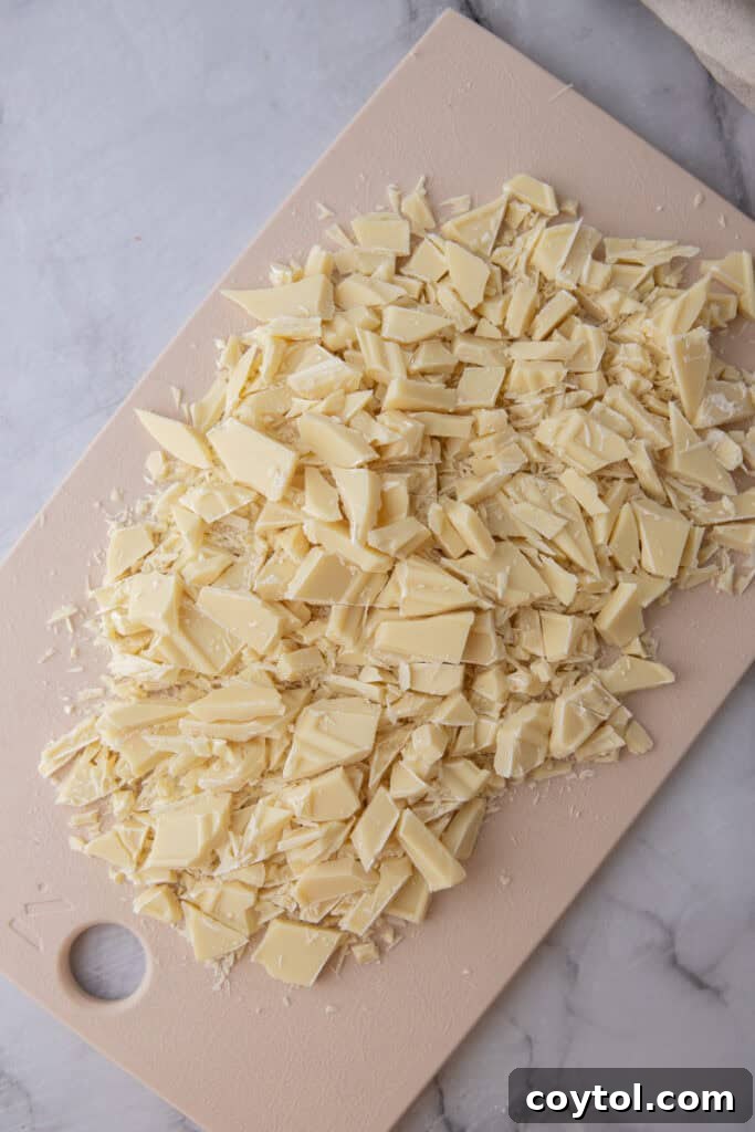 The Ultimate White Chocolate Ganache Recipe 5 chopped pieces on a cutting board
