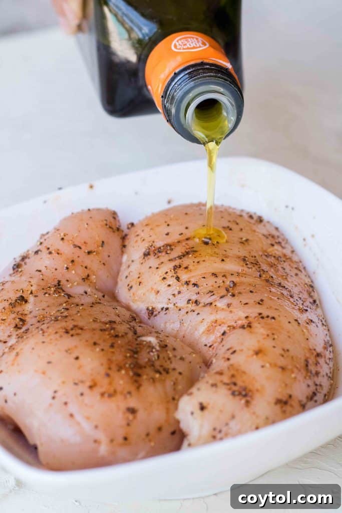 Massaging the olive oil and spices into the chicken breasts to ensure even coating.