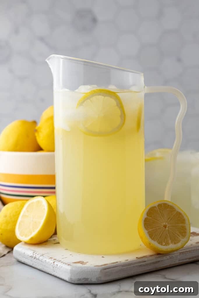 Homemade lemonade served in a glass pitcher with lemon slices and ice