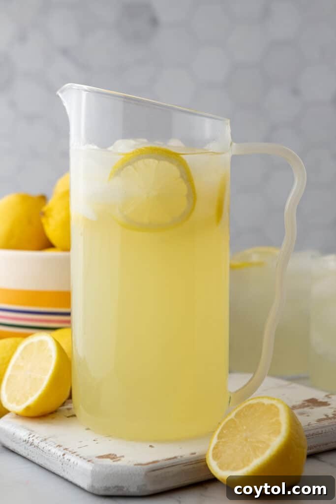 Finished homemade lemonade in a pitcher with ice and lemon slices