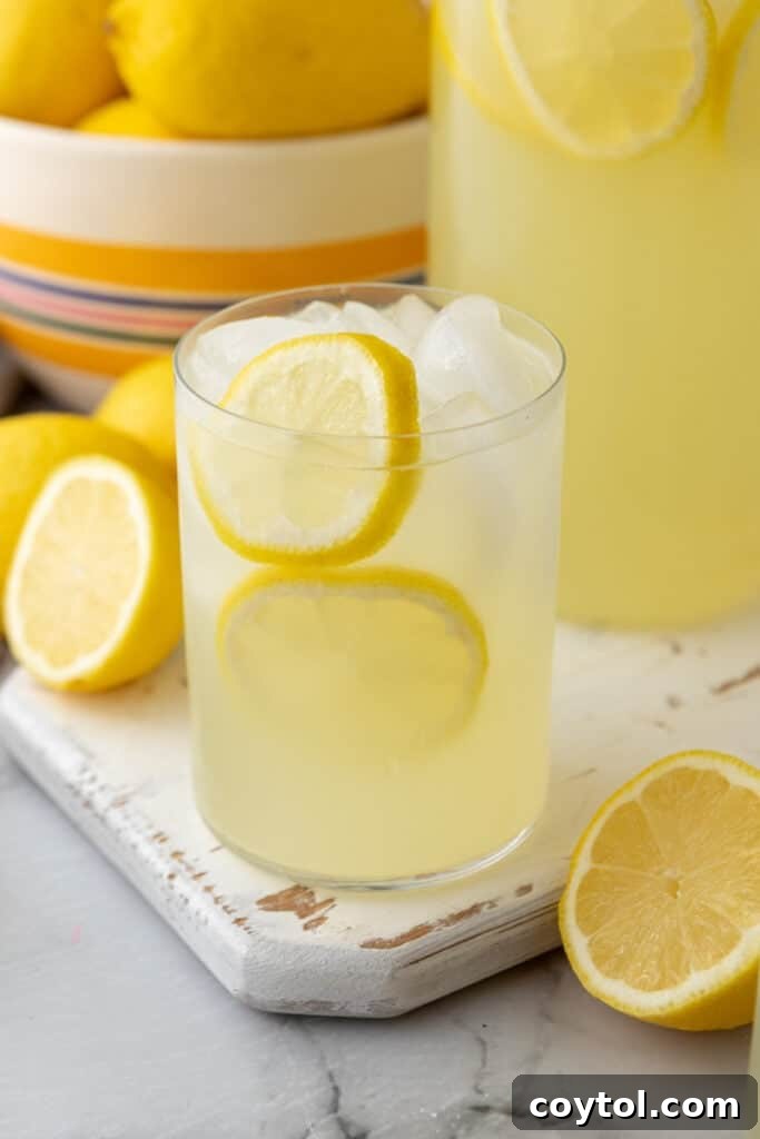 A glass of homemade lemonade with lemon slices, ice, and a straw
