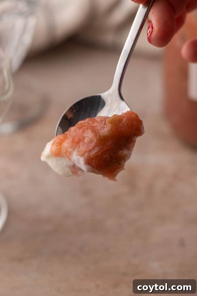 Homemade Rhubarb Sauce Recipe on a spoon, glistening and ready to eat.