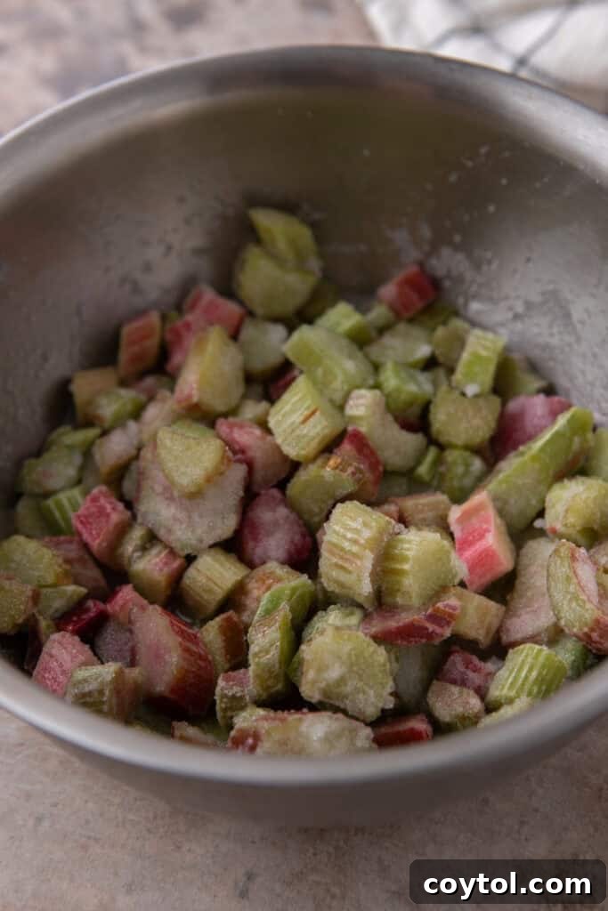Close-up of rhubarb and sugar mixture in a pot, starting to release liquids.