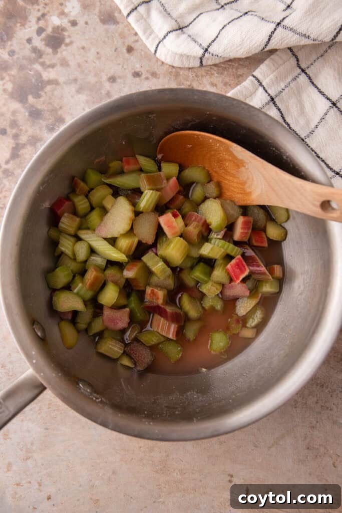 Rhubarb cooking in a pot on medium heat, beginning to break down.