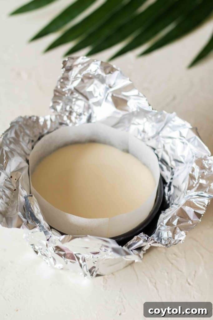 Unbaked cheesecake batter poured over graham cracker crust in mini pan