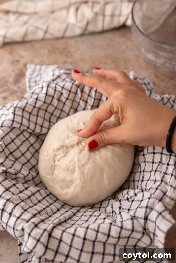 Sourdough dough being gently placed into a floured proofing basket.