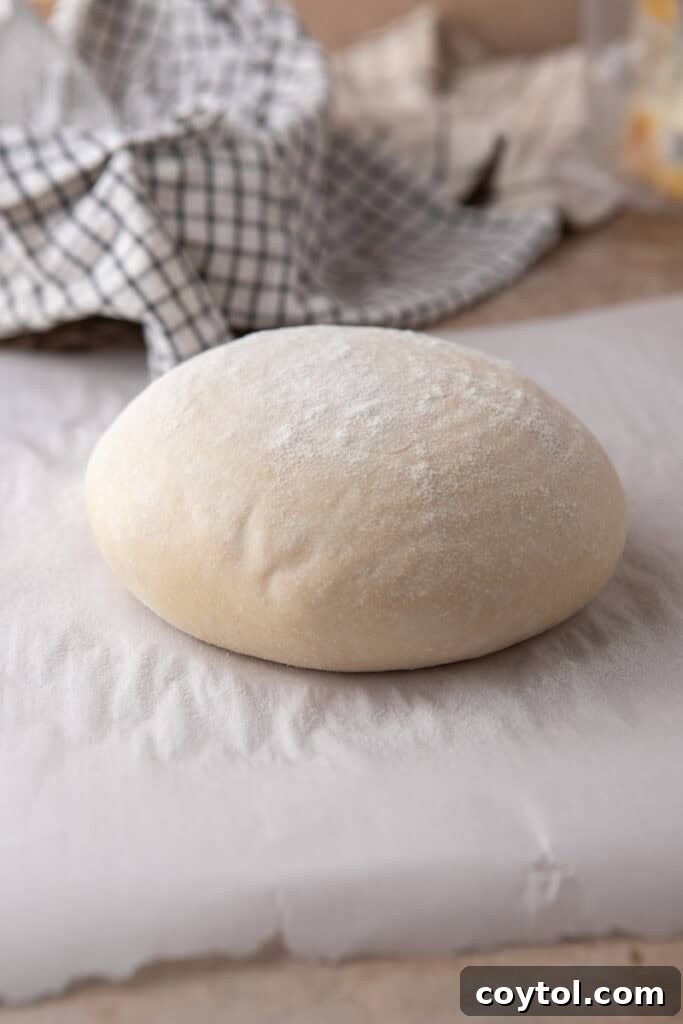 Scored same day sourdough bread loaf on parchment paper, ready for baking.