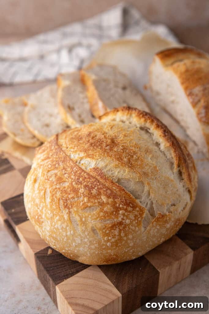 A freshly baked same day sourdough bread loaf sitting on a wooden cutting board, ready to be sliced.