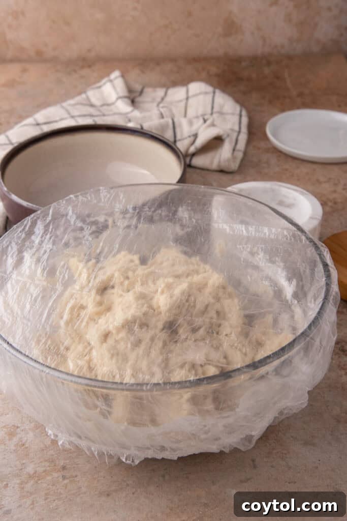 Sourdough dough resting in a bowl, covered with plastic wrap, during the fermentolyse stage.