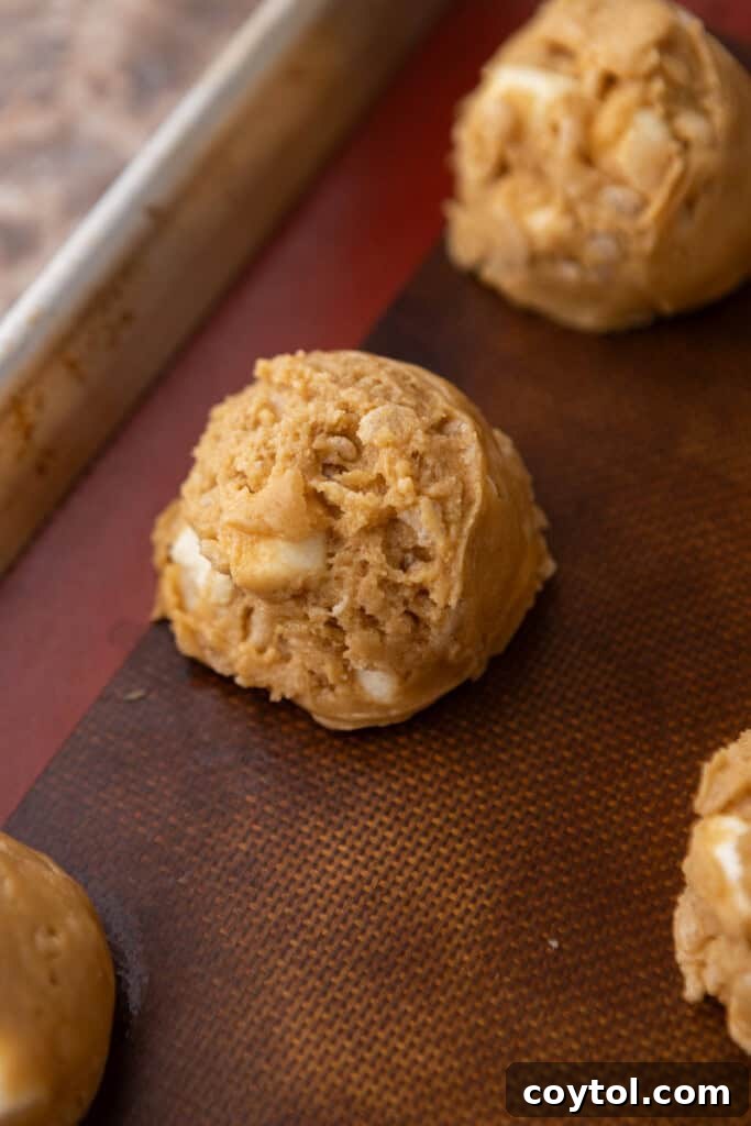 Scooped cookie dough portions neatly arranged on a baking sheet, spaced out for baking.