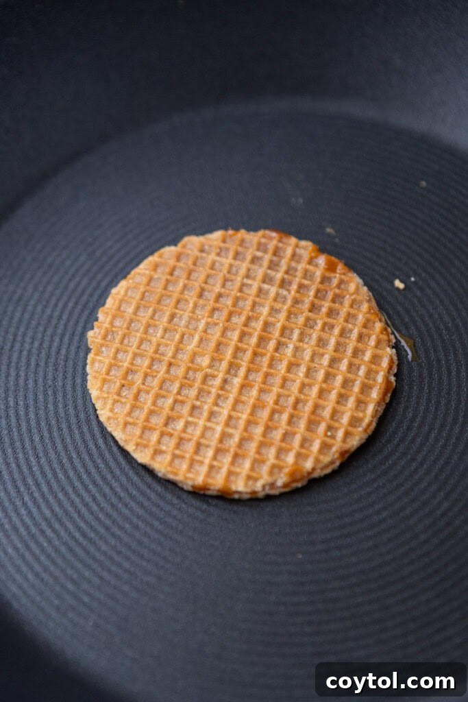Ultimate Stroopwafel Choco Tacos Caramel Chocolate Perfection 5 A stroopwafel cookie being gently warmed on a flat surface.