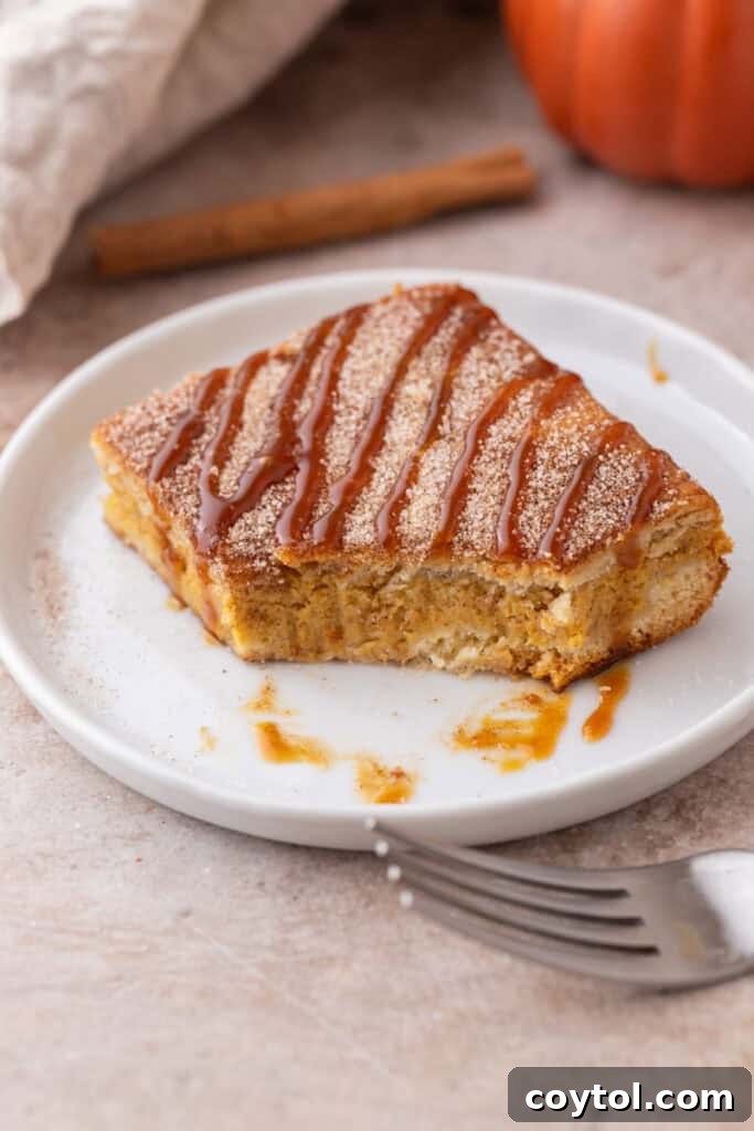 A churro pumpkin cheesecake bar on a plate with a bite taken out, revealing the creamy pumpkin cheesecake layer and the crisp churro crust.
