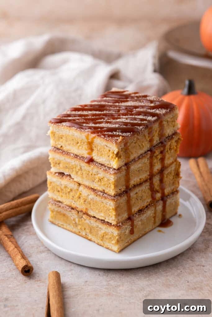 Stacked churro pumpkin cheesecake bars on a decorative plate, garnished with a light dusting of cinnamon.