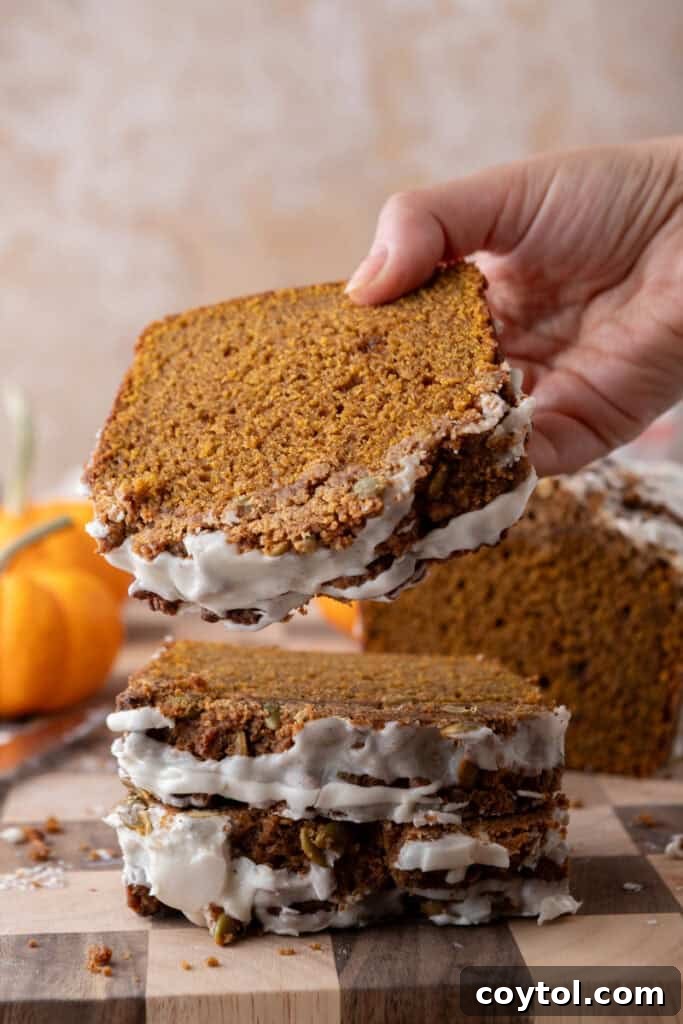 A hand reaching for a slice of Streusel Pumpkin Bread, showcasing its moist texture and crunchy topping.