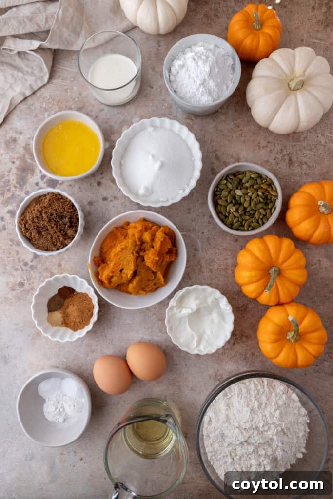 A collection of fresh ingredients laid out for making Streusel Pumpkin Bread, including pumpkin puree, spices, and flour.