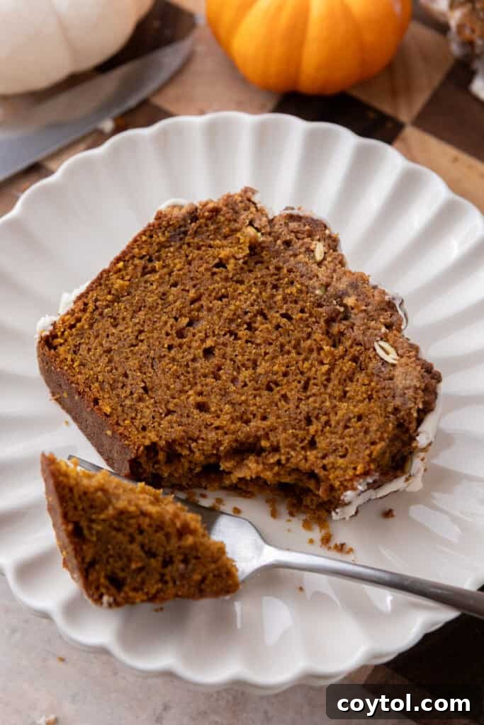 A perfectly sliced piece of Streusel Pumpkin Bread on a plate, showing its moist interior, streusel topping, and glaze.