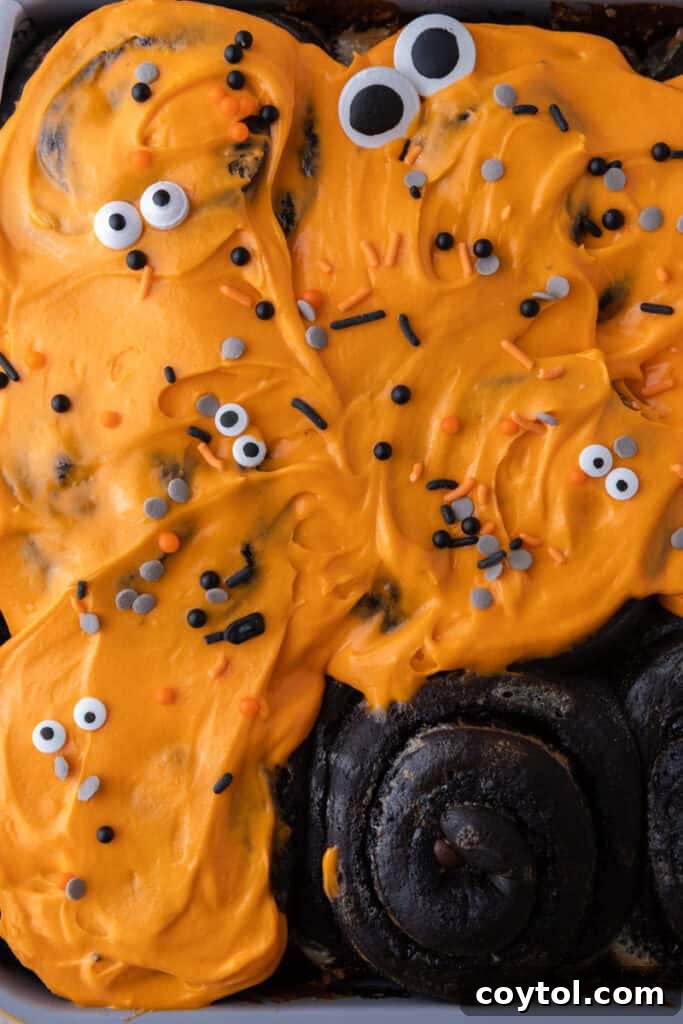 Black Cocoa Cinnamon Rolls being topped with icing