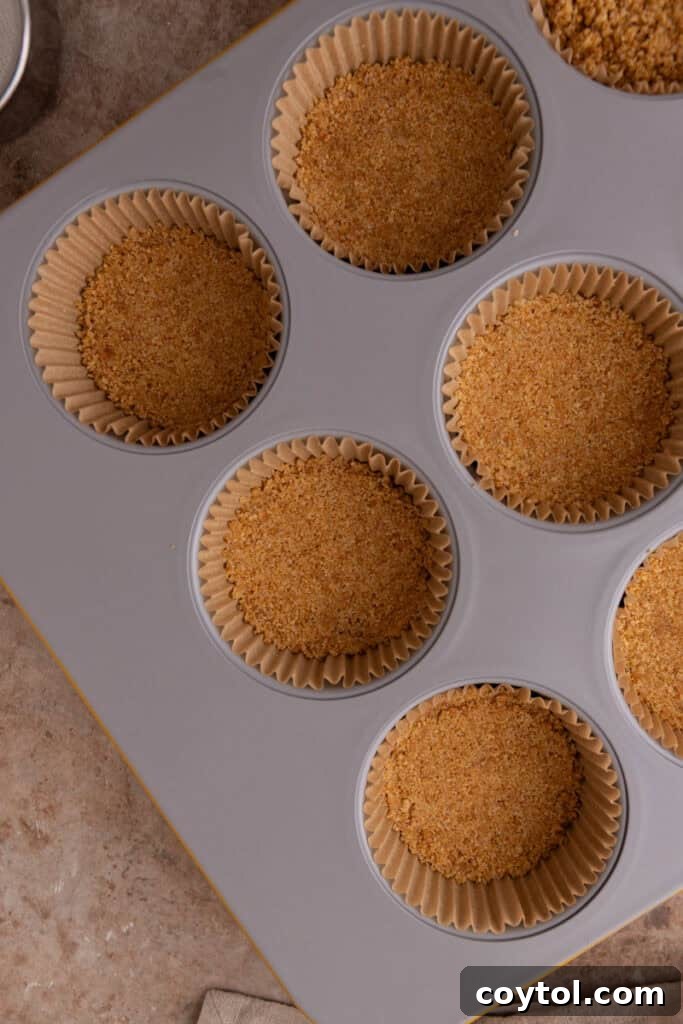 Irresistible Pecan Pie Cheesecake Bites 12 Baked and slightly cooled graham cracker crusts in a muffin tin, forming a solid base.