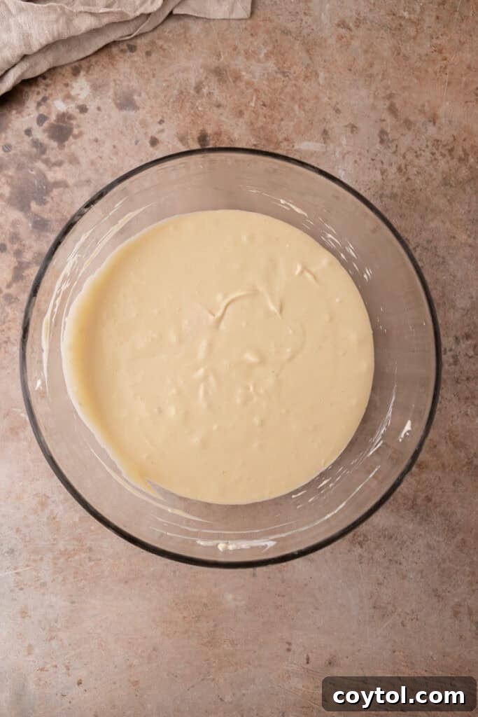 Irresistible Pecan Pie Cheesecake Bites 17 Smooth cheesecake filling in a mixing bowl, ready to be poured over crusts.