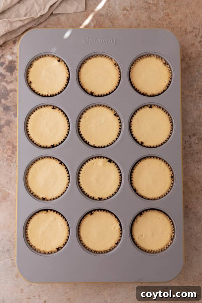 Irresistible Pecan Pie Cheesecake Bites 19 Baked mini cheesecakes in a muffin tin, showing their perfectly set and lightly golden tops.