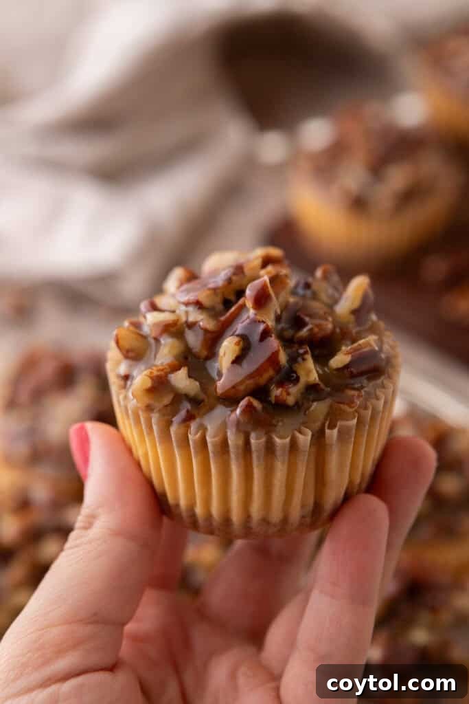 Irresistible Pecan Pie Cheesecake Bites 27 A hand holding a Mini Pecan Pie Cheesecake, showcasing its perfect individual portion and delicious topping.