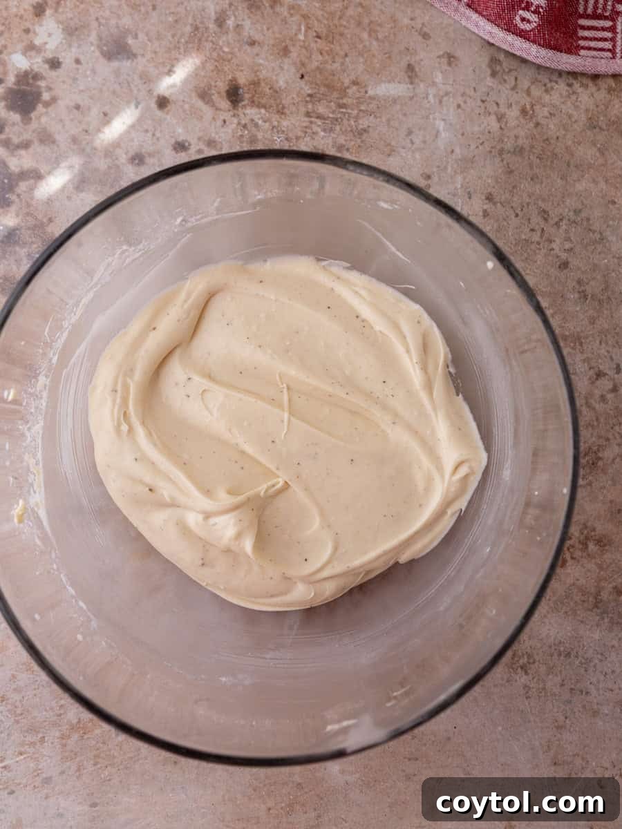 Cream cheese cinnamon roll frosting in a glass bowl, whipped smooth and fluffy