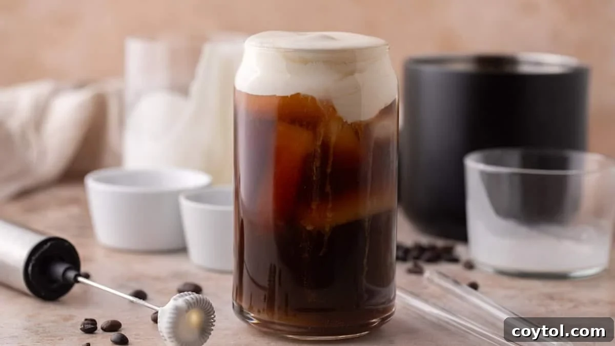 Iced cold brew in a glass topped with thick homemade protein cold foam, layered with creamy foam and coffee.