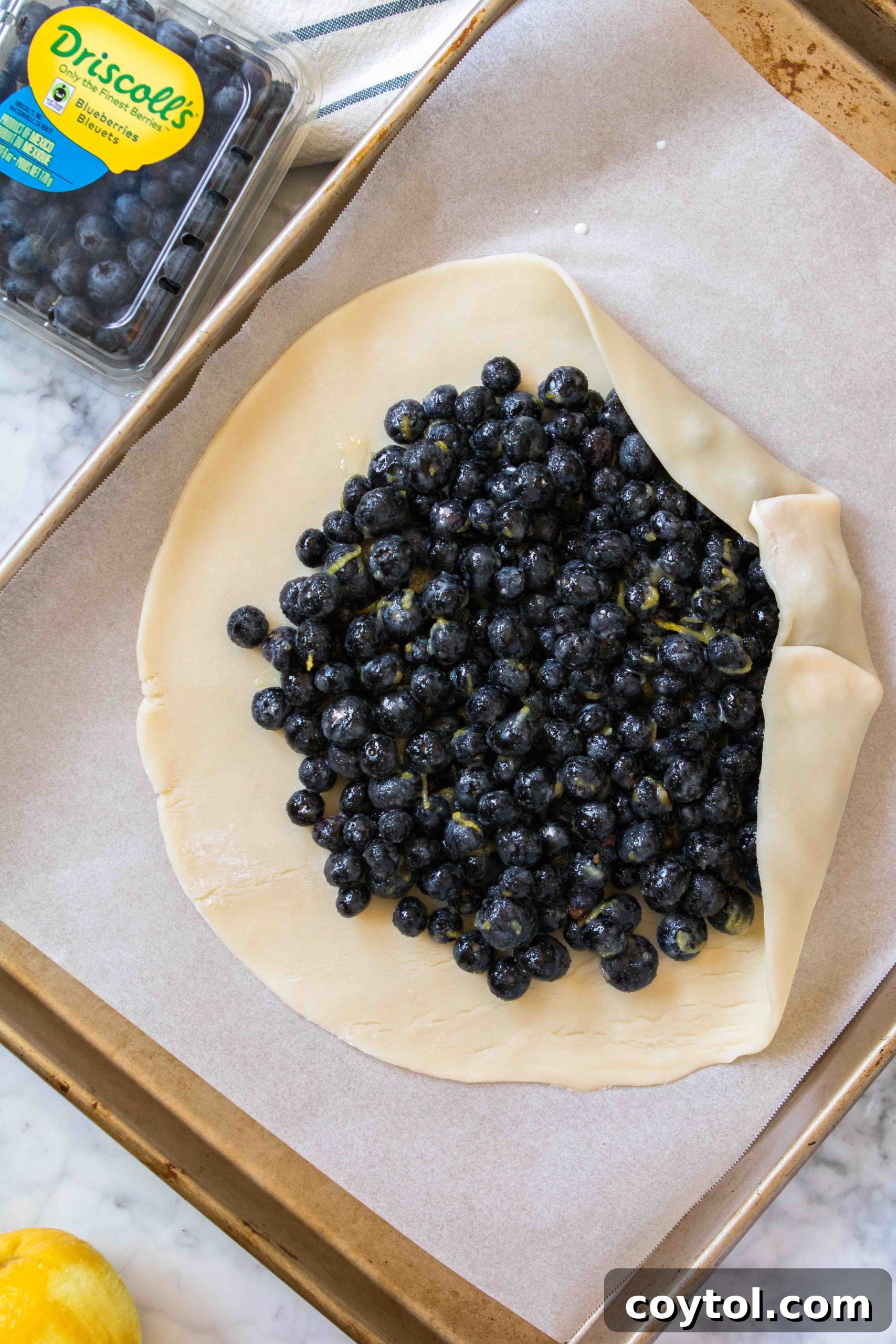 Folding the edges of the pie crust over the blueberry filling