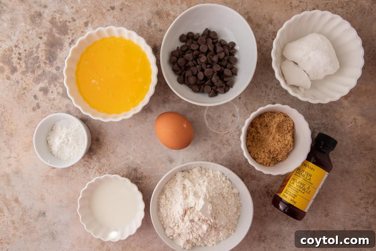 Martha Stewart's Chocolate Chip Cookies Crumbl-Style 3 Overhead shot of ingredients for Crumbl Martha Stewart Chocolate Chip Cookies including melted butter, sugars, flour, egg, vanilla, and chocolate chips.