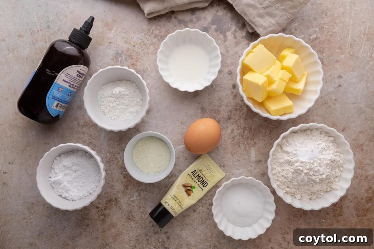 Carefully arranged ingredients for Danish butter cookies on a rustic kitchen counter, including softened butter, flour, various sugars, vanilla bean paste, egg yolk, milk powder, and cornstarch, ready for baking.