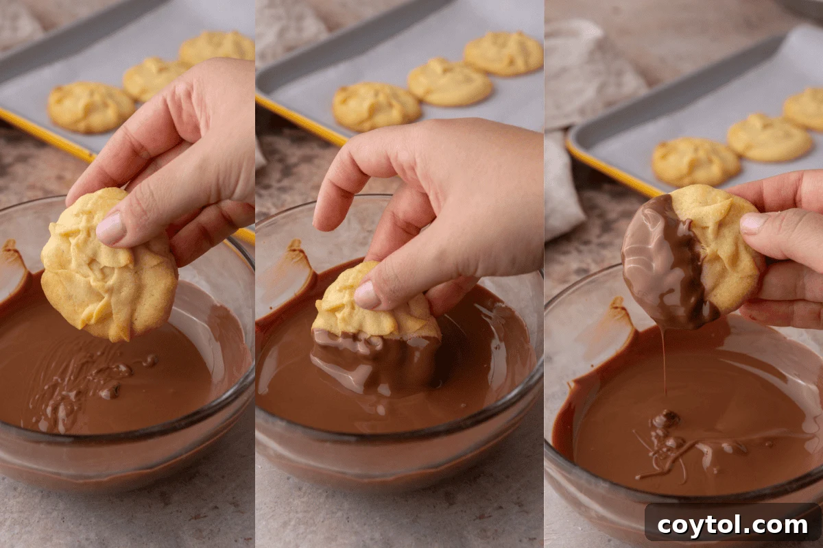 A hand gently dips a baked Danish butter cookie into a bowl of melted chocolate, illustrating an optional finishing step.