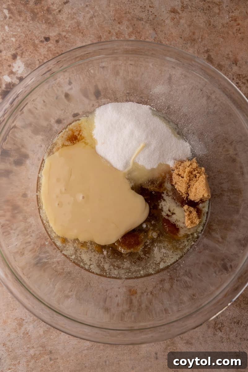 Butter, sugars, sweetened condensed milk, and corn syrup in a bowl before mixing