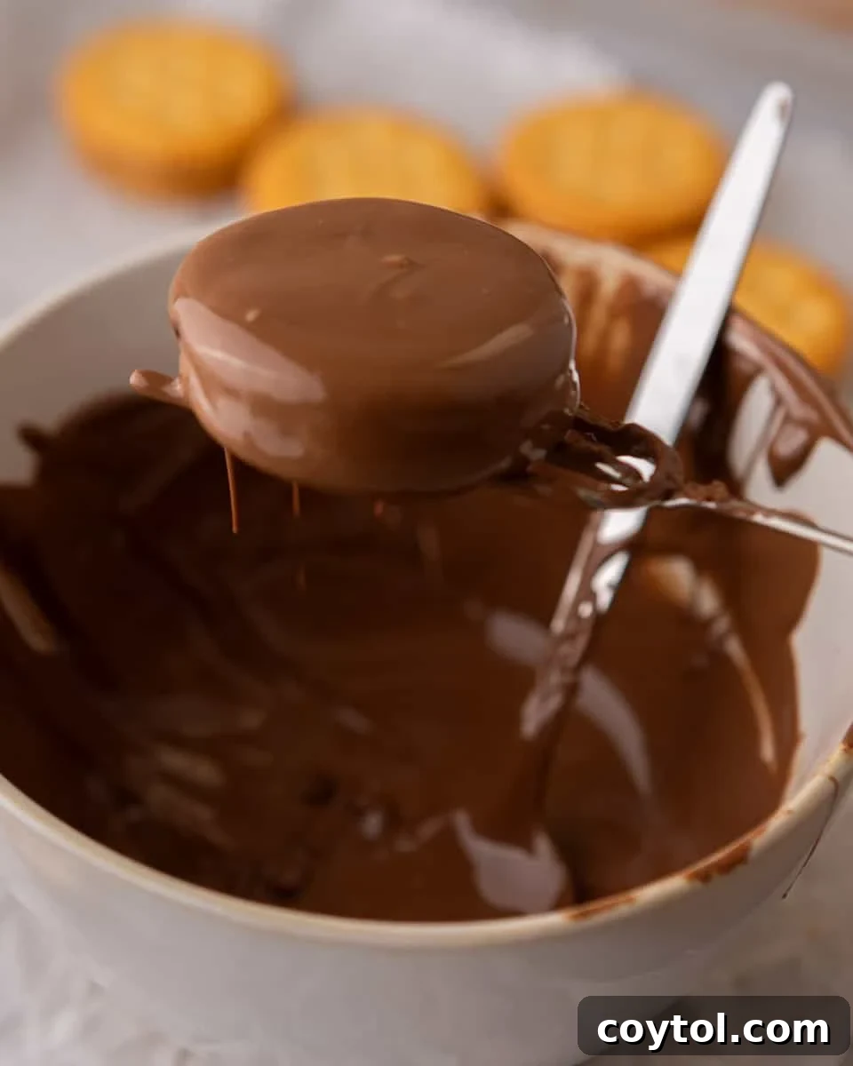 Easy No-Bake Ritz Peanut Butter Chocolate Sandwiches 6 Ritz peanut butter cookies being dipped into melted milk chocolate