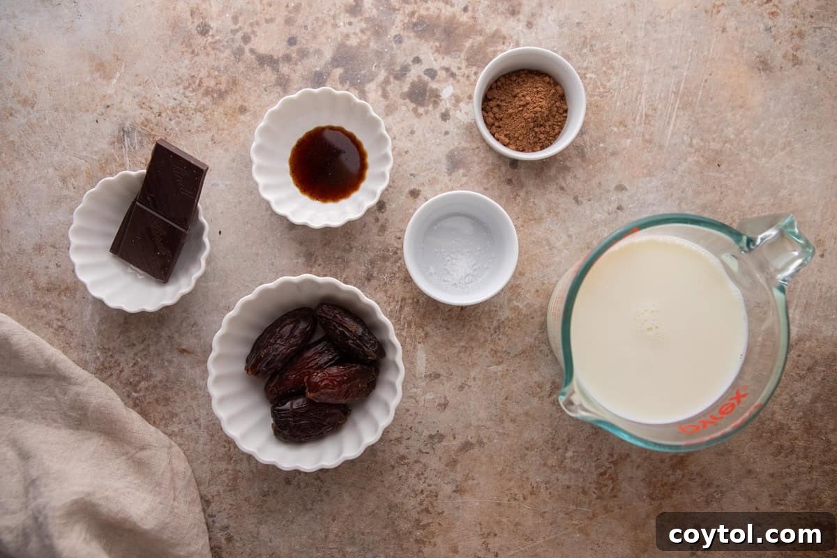 Various ingredients for date sweetened hot chocolate, including Medjool dates, cocoa powder, dark chocolate, and milk, neatly arranged on a kitchen countertop.