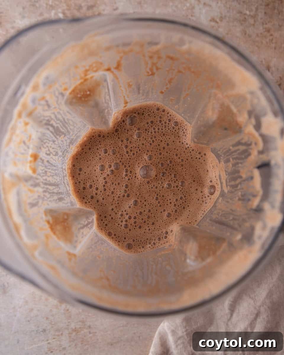 The blended hot cocoa mixture in a high-speed blender, appearing smooth and frothy, ready for heating.