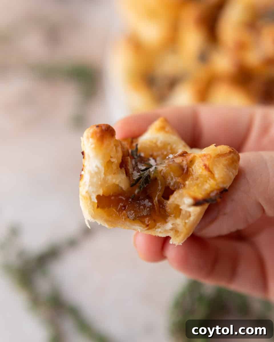 Sweet and Savory Brie Fig Pastry Bites 7 Close-up of a single brie and fig jam puff pastry cup with a bite taken, revealing the gooey brie, sweet fig jam, and flaky pastry layers inside.