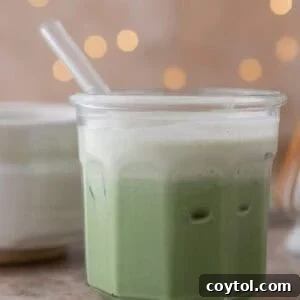 Velvety Salted Maple Matcha Frost 7 Iced salted matcha latte with a cream top and flickering lights behind it.