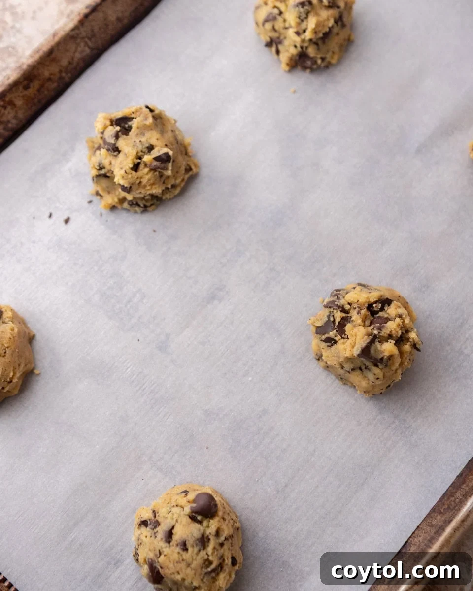 Cream cheese cookie dough balls on parchment-lined baking sheet