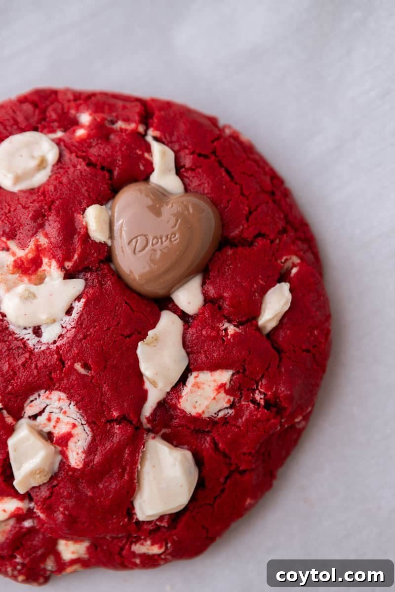 A close-up of a single-serve red velvet cookie featuring abundant white chocolate chunks and a beautifully cracked, glossy top, ready to be enjoyed.