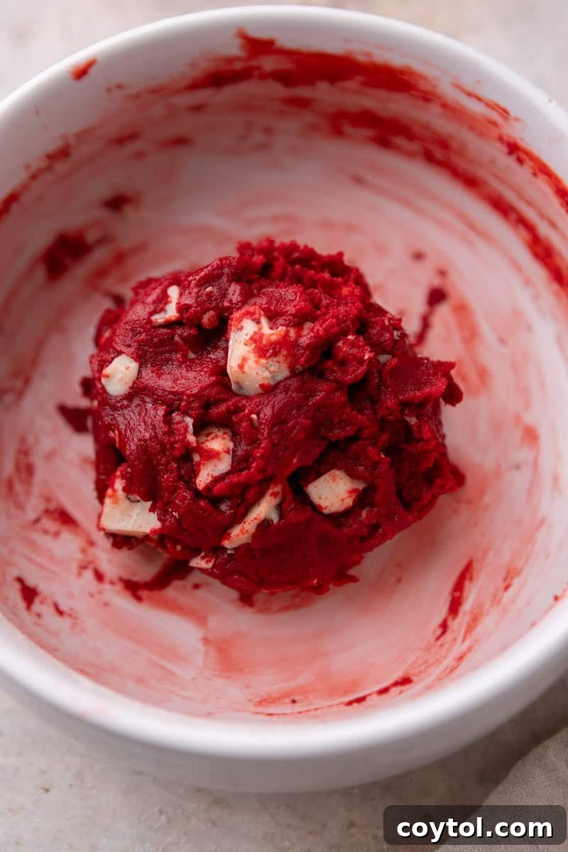 The red velvet cookie dough formed into one large, perfectly rounded ball, ready to be placed on the baking sheet.
