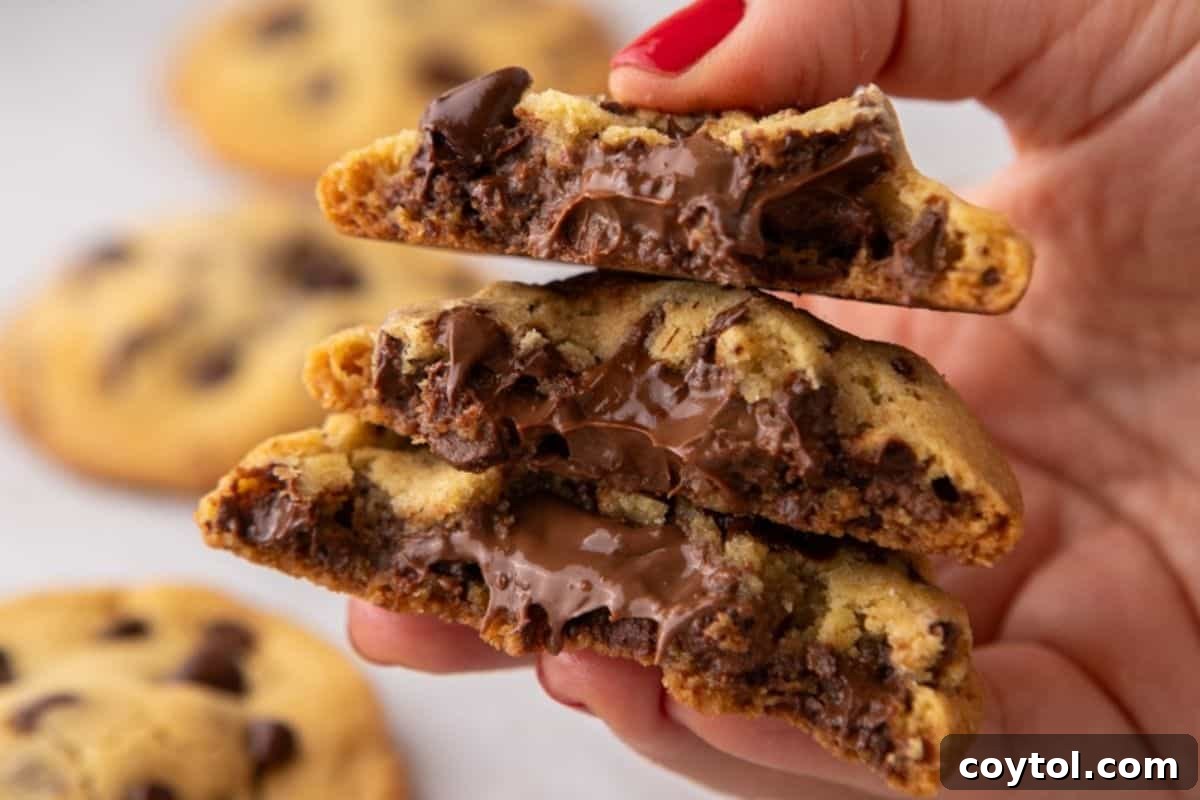 Hand holding a Nutella-stuffed chocolate chip cookie with melted hazelnut filling