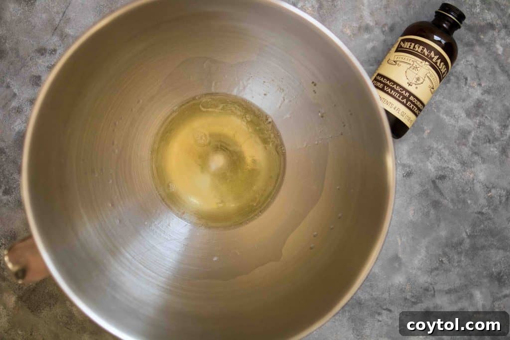 Process photo showing egg whites and sugar being whipped into a foamy consistency for meringue.