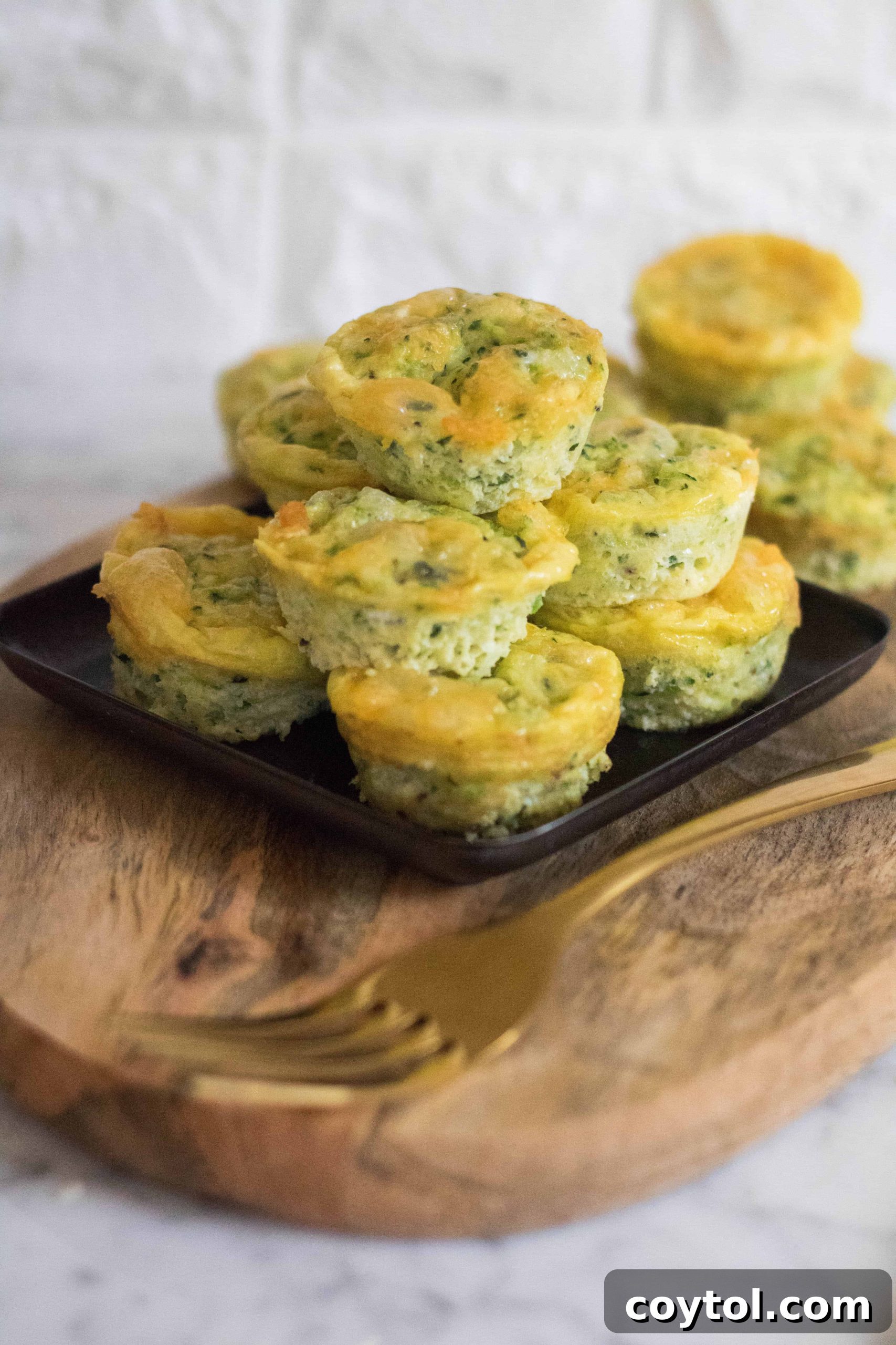A vibrant display of baked Mini Breakfast Zucchini Frittatas on a rustic wooden board, ready to be served.