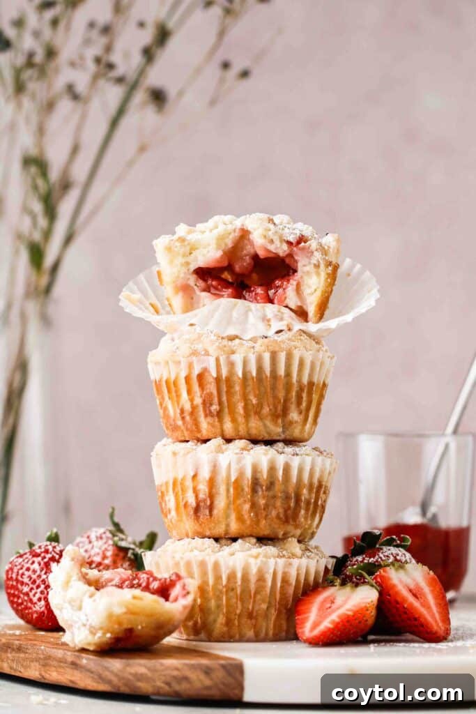 Stack of luscious strawberry stuffed muffins with a golden streusel topping, ready to be enjoyed.
