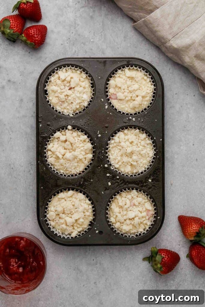 Muffins topped generously with streusel before baking, ready for the oven.