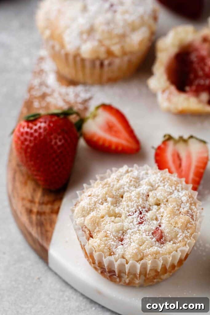 A vibrant strawberry jam muffin with streusel topping, showcasing its golden color and inviting texture.